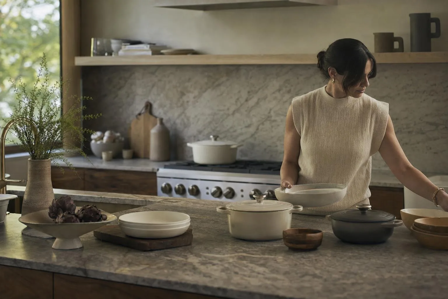 Modern kitchen counter with stoneware plates, a cast iron pan, and wooden utensils